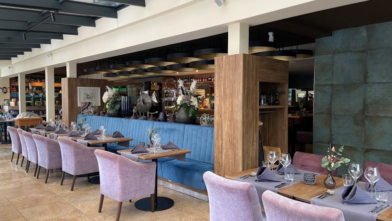 Elegantes Restaurant mit gedeckten Tischen und lila Stühlen.