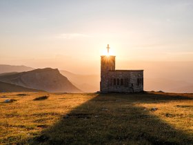 Die sanften Hügel der Wiener Alpen umarmen die kleine, charmante Kapelle, die im goldenen Licht der untergehenden Sonne erstrahlt. Ihre silhouette hebt sich majestätisch gegen den Himmel ab und lädt Wanderer ein, einen Moment der Stille und Besinnung zu genießen. Hier, wo die Natur und die Spiritualität harmonisch verschmelzen, wird jeder Besuch zu einem unvergesslichen Erlebnis.