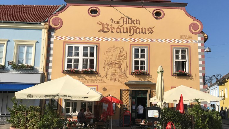 Fassade eines traditionellen Brauhauses mit Sonnenschirmen und Sitzbereich im Freien.