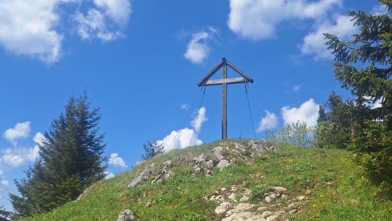 Gipfelkreuz aus Holz, davor ein Pfad dorthin