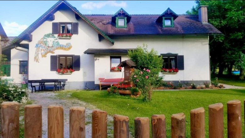 Ein traditionelles Haus mit Blumen an den Fenstern und einem Holzzaun im Vordergrund.