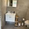 Modernes Badezimmer mit Waschbecken, Spiegel, Toilette und Regalen.