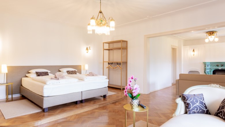 Elegantes Schlafzimmer mit Doppelbett, Kronleuchter und Kamin.