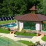Außenansicht eines Wellnessbereichs mit Pool und Pavillon im Grünen.