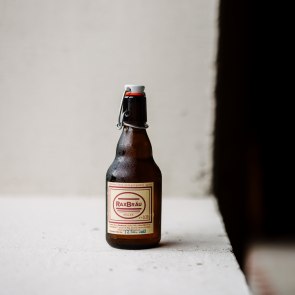 Eine kleine Bierflasche vor einem wei&szlig;en Hintergrund mit dem Rax Br&auml;u Etikett