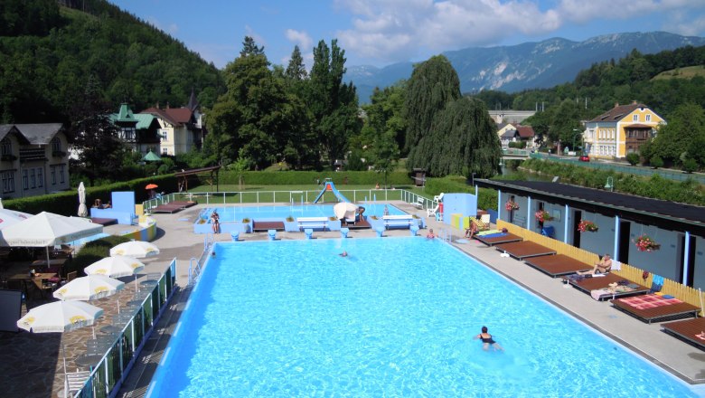 Freibad Payerbach mit Schwimmern und umliegender Landschaft.