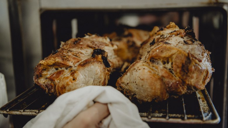 Frisch gebratenes Schweinefleisch wird aus dem Ofen genommen.