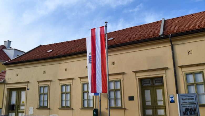 Außenansicht des Museums Neunkirchen mit österreichischer Flagge und Informationsschild.