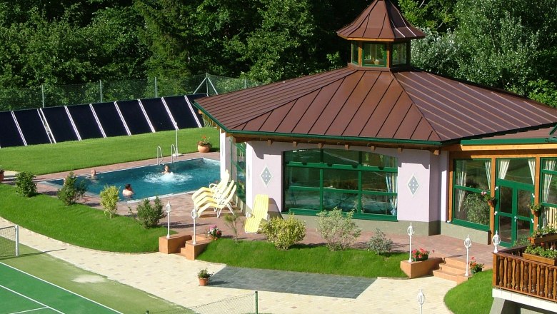 Außenansicht eines Wellnessbereichs mit Pool und Pavillon im Grünen.