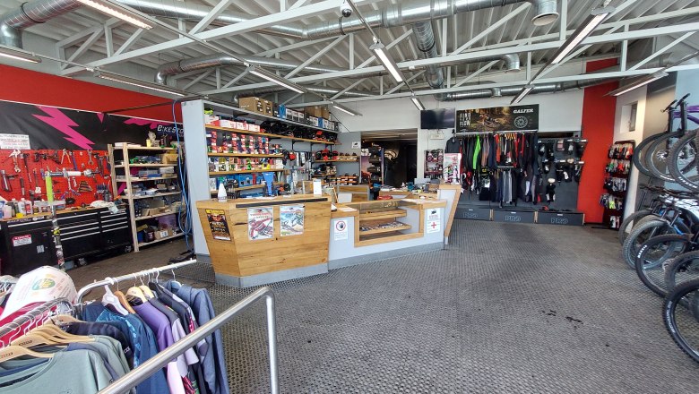 Innenansicht eines Fahrradgesch&auml;fts mit Werkstattbereich, Verkaufstresen und Fahrradzubeh&ouml;r.