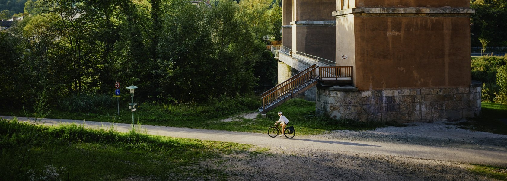 Eine Frau fährt auf dem Rad neben einem Viadukt