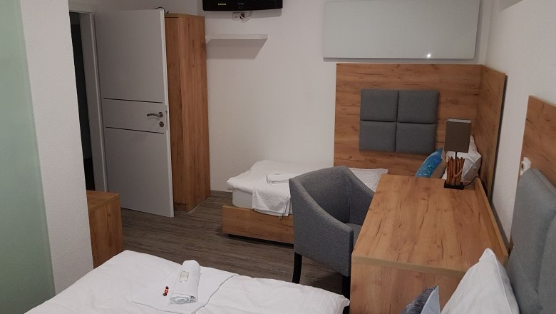 Hotelzimmer mit Holzmöbeln, zwei Betten, einem Schreibtisch und einem Fernseher an der Wand.