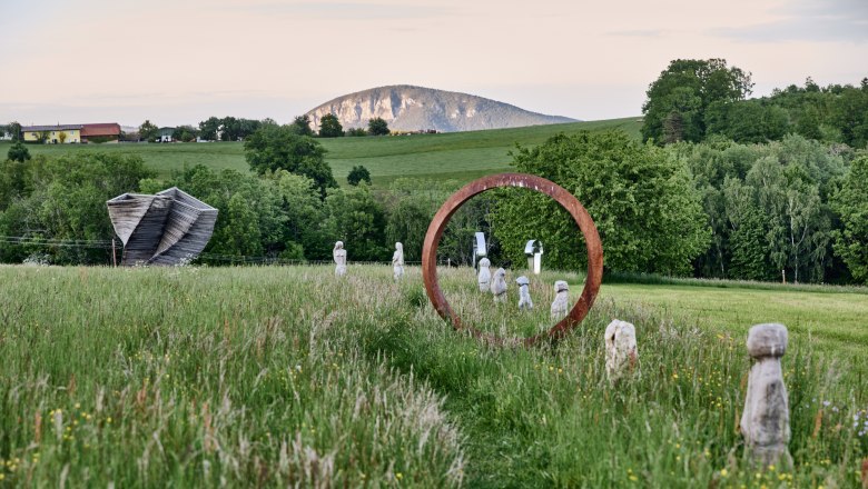 Skulpturenpark mit Kunstwerken und Berg im Hintergrund.