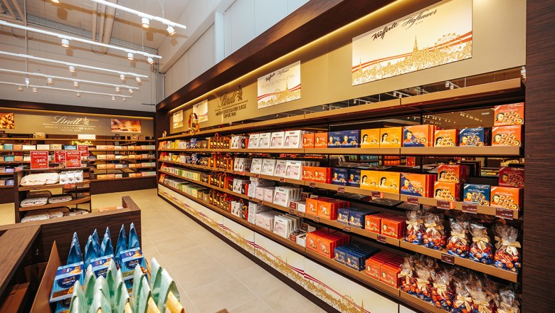 Innenansicht eines Lindt & Spr&uuml;ngli Shops mit Regalen voller Schokolade und S&uuml;&szlig;igkeiten.