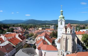Ausblick auf Neunkirchen mit H&auml;usern, Kirche und Bergen im HIntergrund.