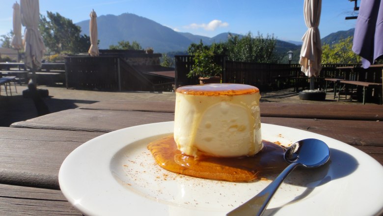 Ein Teller mit Schafkäse, Honig und Zimt auf einer Terrasse mit Bergblick.