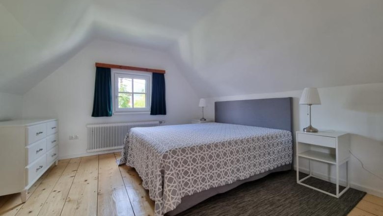 Schlafzimmer mit Doppelbett, Nachttischen und Kommode.