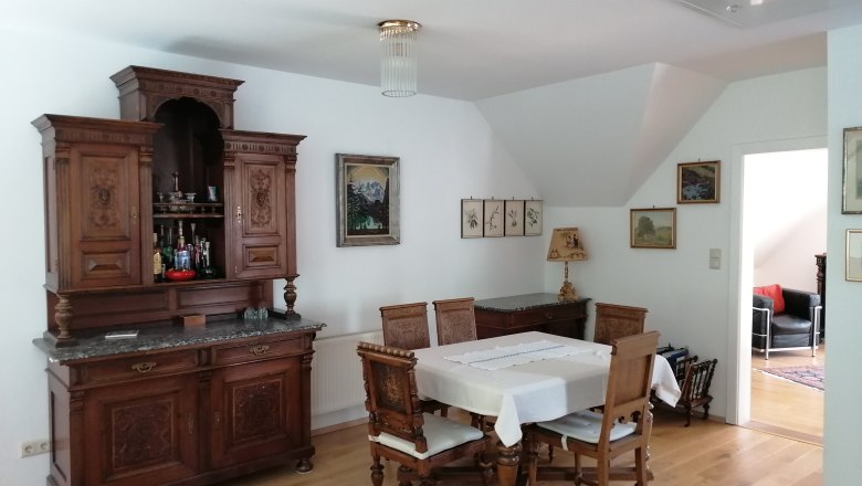 Essbereich mit antikem Holzmöbel und Esstisch mit Stühlen.