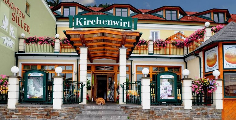 Eingang des Restaurants Kirchenwirt mit Blumen und Schildern.