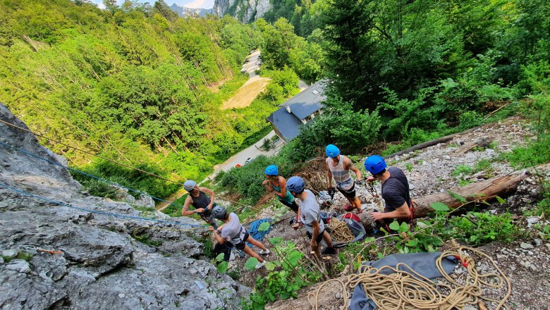 Gruppe von Kletterern mit Helmen an einem Felsen im Wald.
