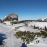 Winterlandschaft mit dem Ottohaus und schneebedeckten Bergen im Hintergrund.