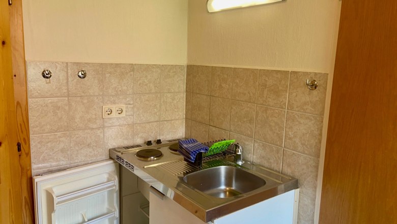 Kleine Küchennische mit Spüle, Herd und Kühlschrank.