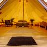 Innenansicht eines luxuriösen Glamping-Zeltes mit Bett, Pflanzen und Möbeln.