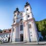 Wallfahrtskirche Maria Schutz mit blauem Himmel und grünen Bäumen im Hintergrund.