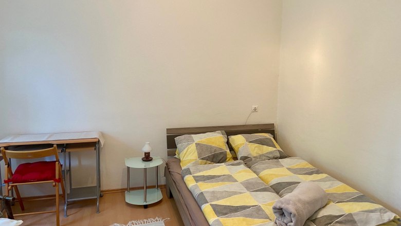 Ein einfach eingerichtetes Schlafzimmer mit einem Bett, einem kleinen Tisch und einem Stuhl.