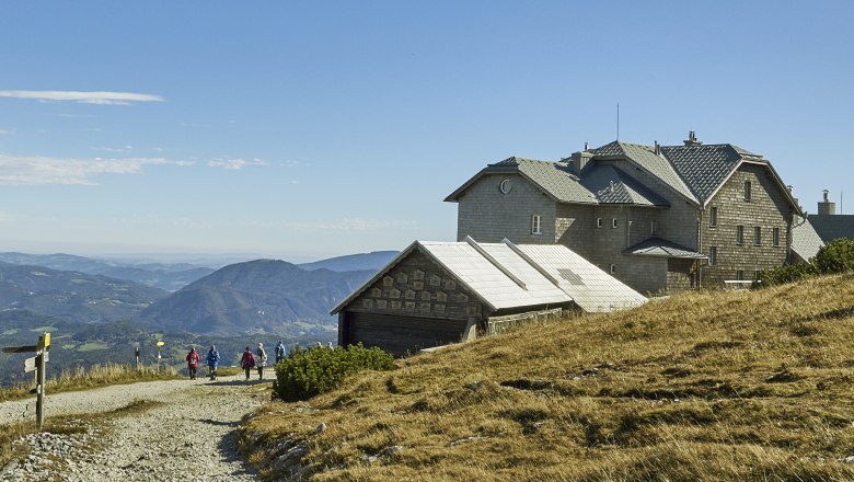 Berglandschaft mit dem Ottohaus und Wanderern auf einem Pfad.