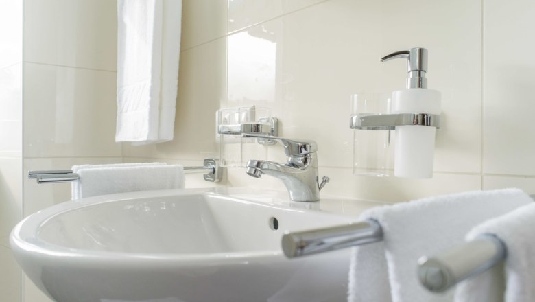 Modernes Badezimmer mit Waschbecken, Handtüchern und Seifenspender.