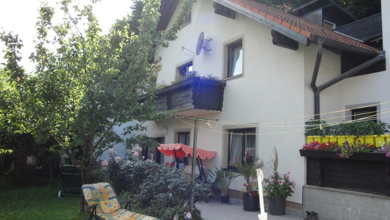 Ein Haus mit Garten, Liegestuhl und Blumen auf der Terrasse.