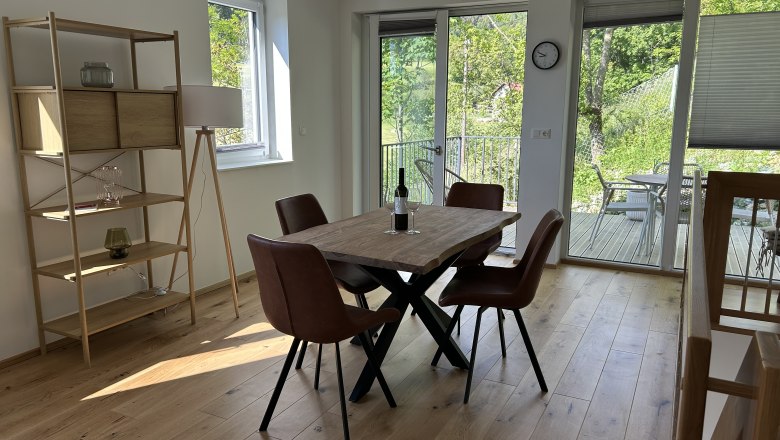 Esszimmer mit Holztisch, braunen Stühlen und Blick auf Terrasse und Garten.