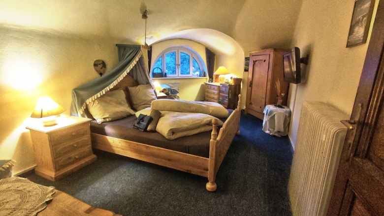 Gemütliches Schlafzimmer mit Holzmöbeln und gewölbter Decke.