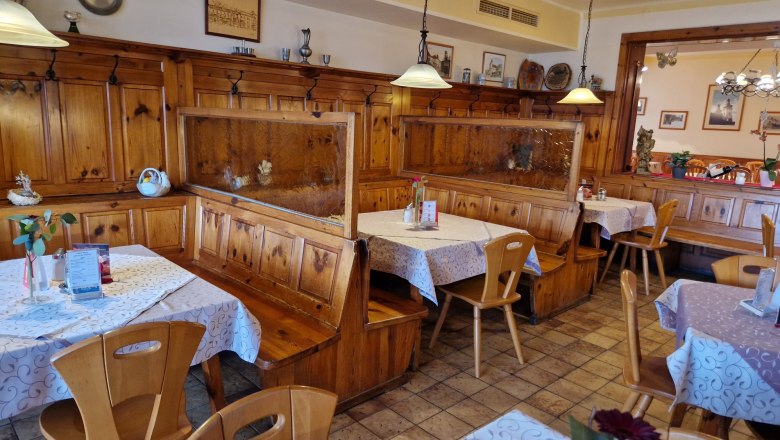 Gem&uuml;tliches Gastzimmer mit Holzm&ouml;beln und dekorierten Tischen.