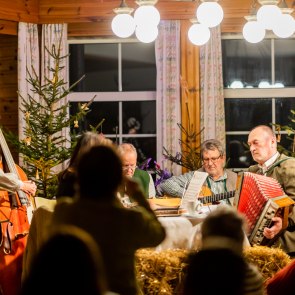 Musikanten sitzen rund um den Tisch und musizieren Weihnachtsmusik
