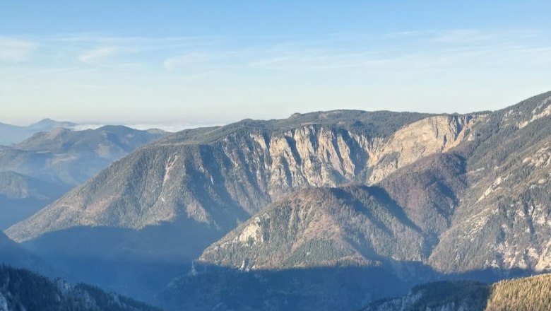 Blick auf eine tiefe Schlucht mit steilen Felswänden und bewaldeten Bergen im Hintergrund unter klarem Himmel.
