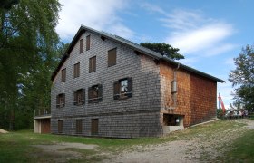 Neunkirchner Haus auf der Flatzer Wand mit Holzfassade und blauen Himmel.