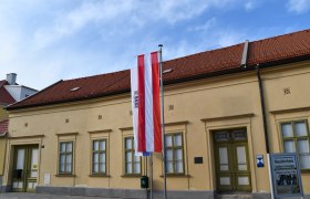 Außenansicht des Museums Neunkirchen mit österreichischer Flagge und Informationsschild.